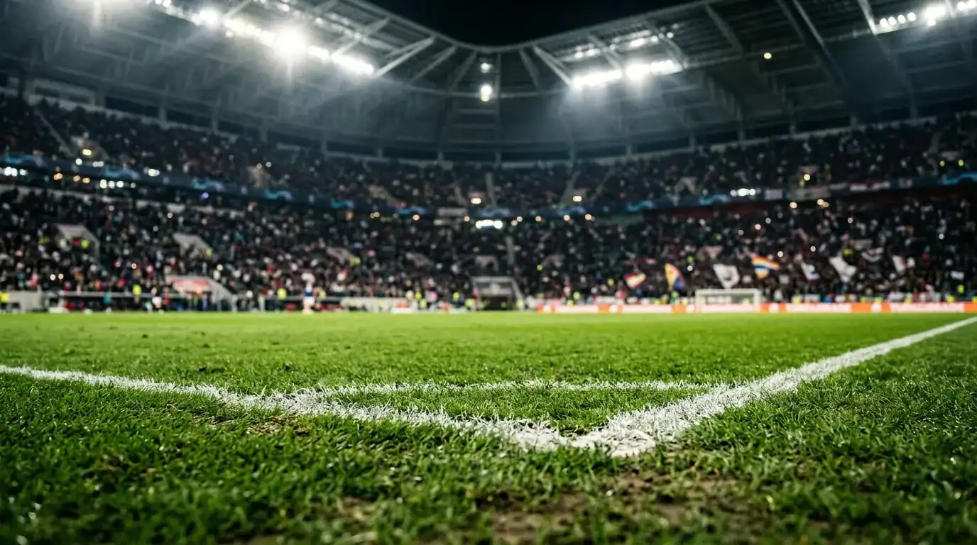 Detalle del césped de un estadio con techo cerrado y focos, ambiente de partido nocturno de cuartos de final, gradas desenfocadas al fondo